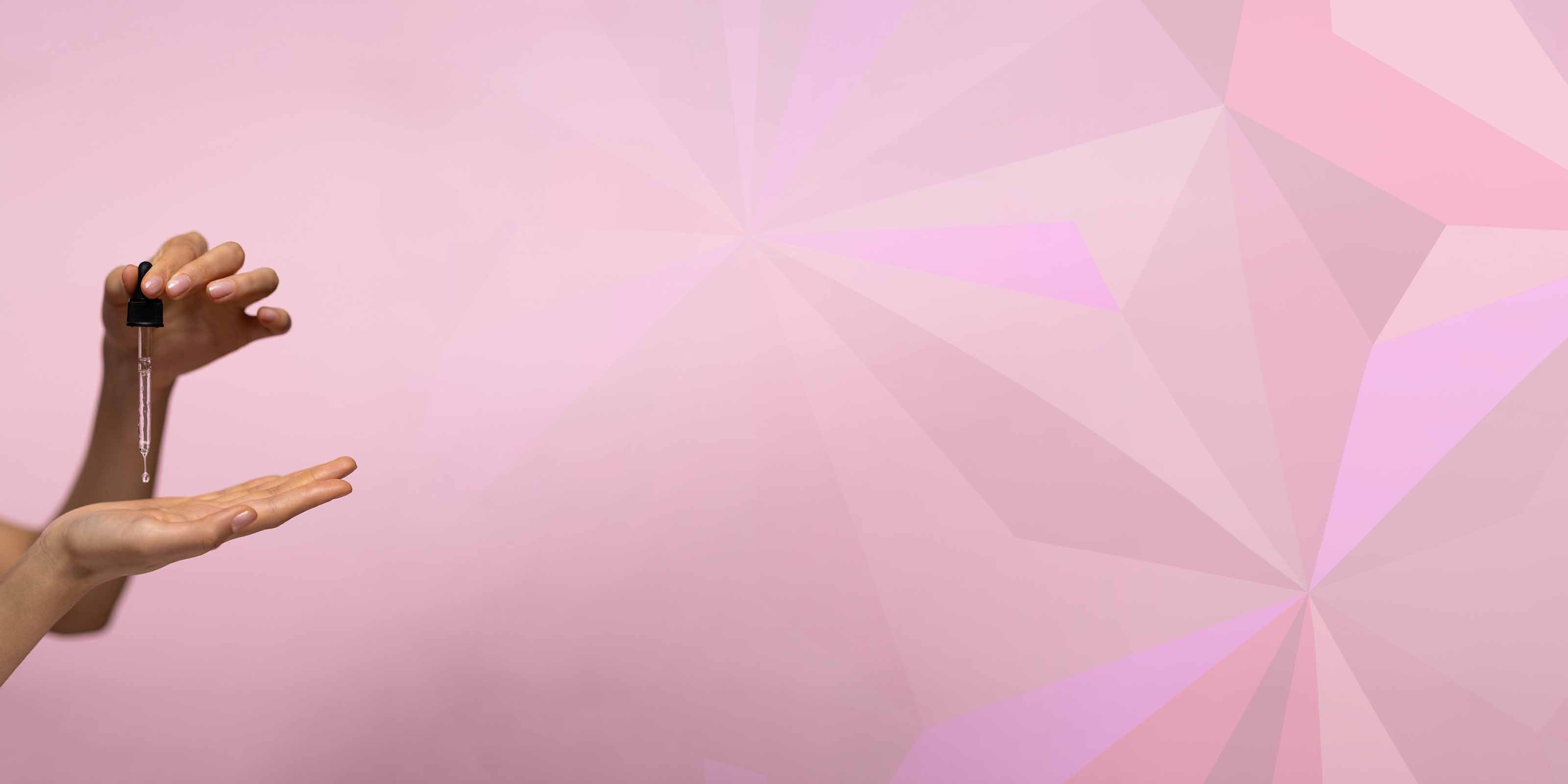 Hand holding a dropper with a pink geometric background