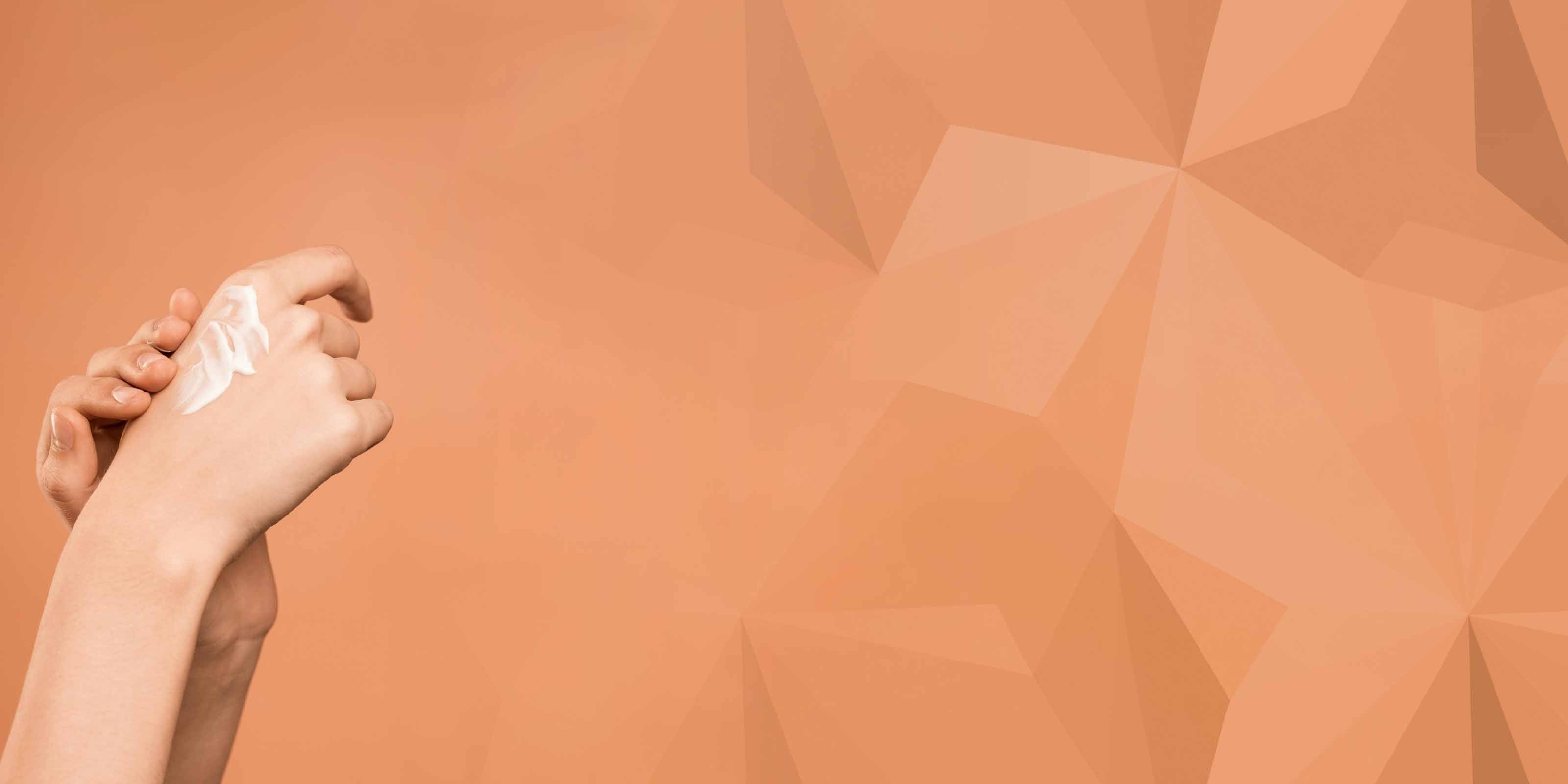 Hand applying cream on a geometric patterned background